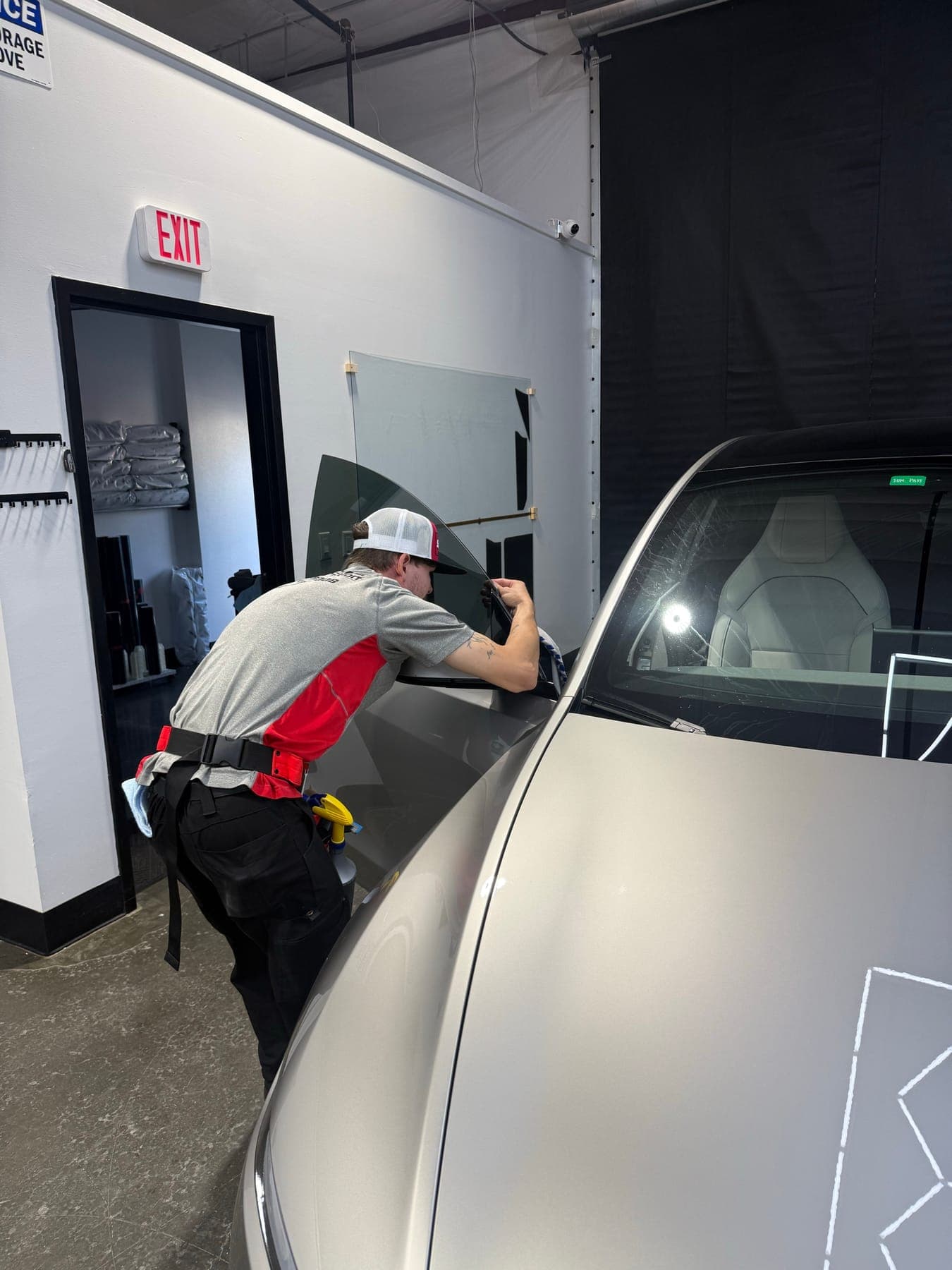 Polished to Perfection installer fitting ceramic window tint on a new Cosmic Silver Tesla Model Y L