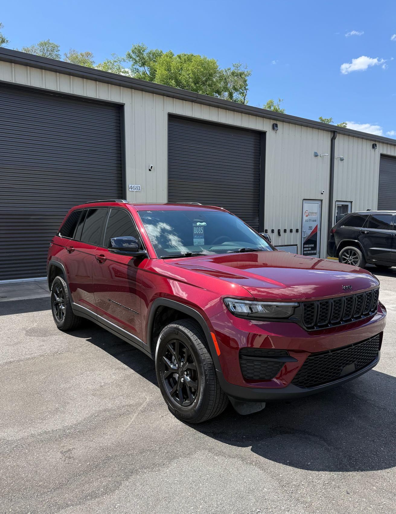 Red 2025 Jeep Grand Cherokee Laredo Altitude with tinted windows parked outside the Polished to Perfection shop