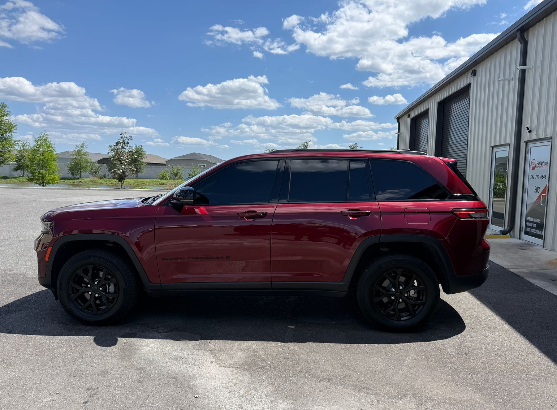 Side profile of a red 2025 Jeep Grand Cherokee Laredo Altitude with ceramic window tint on the side glass